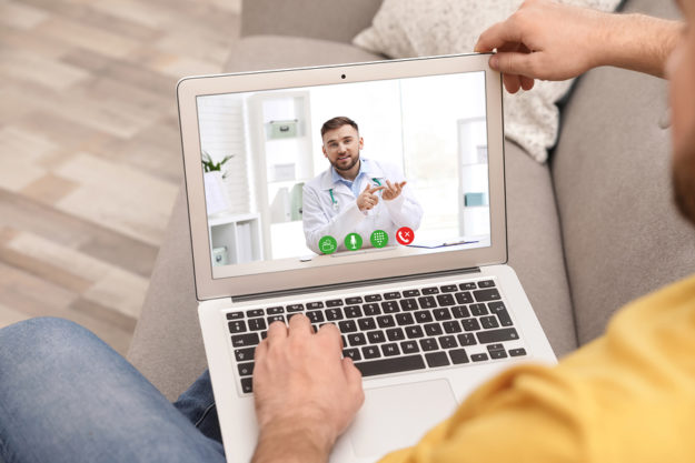 Man Using Laptop For Online Consultation With Doctor Via Video C